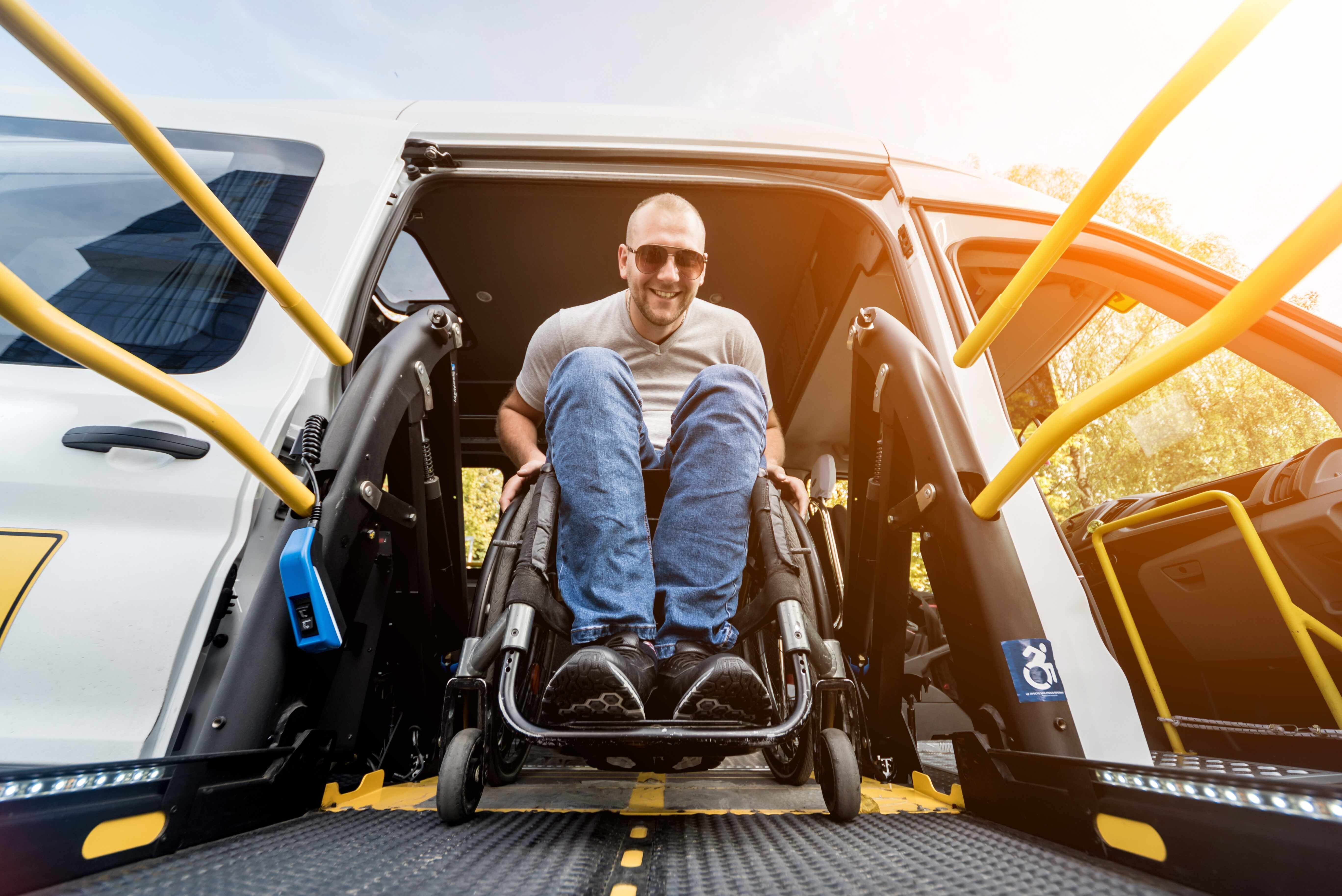 Man in a wheelchair leaving an adapted van, down a ramp